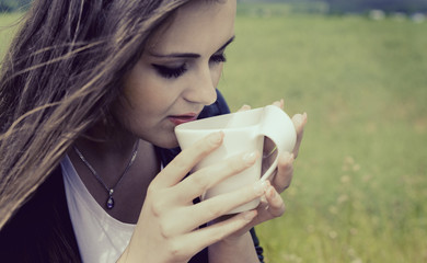 girl drinks coffee with pleasure outdoors