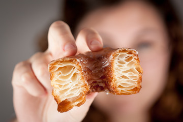 Croissant and doughnut mixture being held by a girl