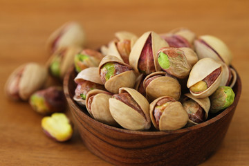 Pistachios with and without shell in wooden bowl