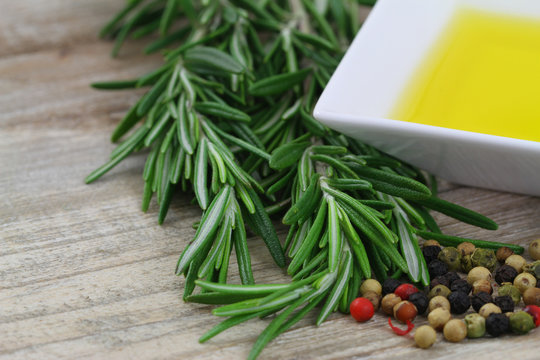 Rosemary, mixed peppers and olive oil on wooden background