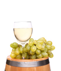 Ripe grapes and wine glass on a wooden barrel
