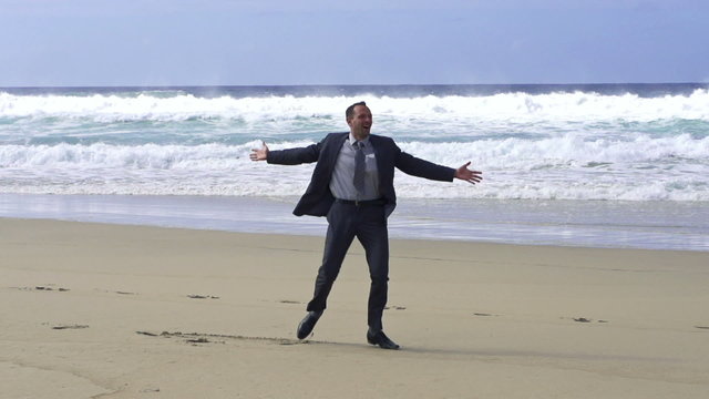 Happy businessman dancing on the beach, slow motion shot at 240f