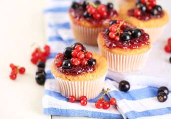 Tasty muffins with berries on white wooden table