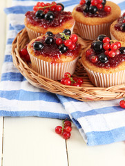Tasty muffins with berries on white wooden table