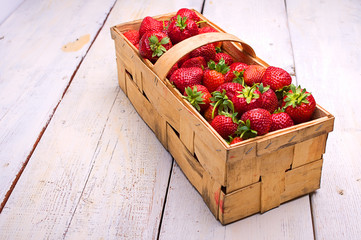 full basket of strawberries on the old, whitewashed boards