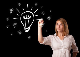 Woman drawing light bulb on whiteboard