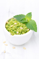 close-up of green pea pesto with mint on a white background