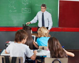 Students Using Tablet And Calculator While Teacher Teaching