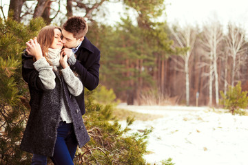Sensual fashion outdoor winter portrait of young beautiful happy smiling couple in love posing together in park kissing