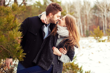 Fototapeta premium Sensual fashion outdoor winter portrait of young beautiful happy smiling couple in love posing together in park having fun 
