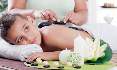 Obraz na płótnie Canvas therapist massaging a young boy in the spa salon
