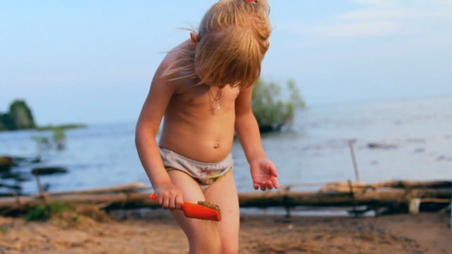 маленькая девочка играет, смотрит  вдаль на воду