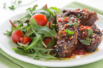 Pork ribs in ginger glaze with salad.