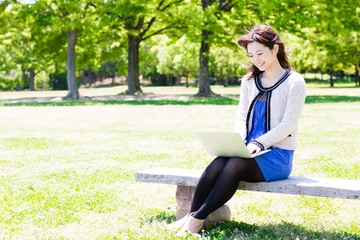 Naklejka na ściany i meble young asian woman using laptop in the park