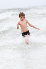 Fototapeta premium kleiner junge spiel glücklich im sand am meer im wasser