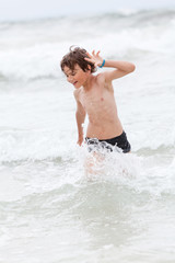 Fototapeta premium kleiner junge spiel glücklich im sand am meer im wasser