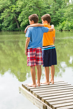 Zwei jugendliche Freunde blicken auf idyllischen Teich