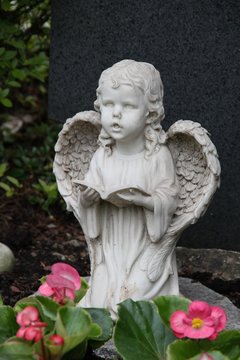 Betender Engel auf einem Grab mit Blumen