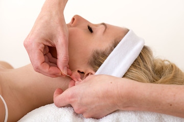 Obraz na płótnie Canvas Homeopath applying an acupuncture needle on ear.