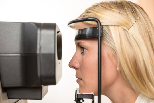 Patientin eines Optikers schaut durch Autorefraktometer