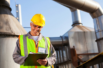 petrochemical engineer recording technical data on clipboard
