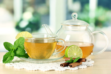 Cup of tea with mint,lime and cinnamon on table in room