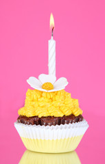 Beautiful cupcake with candle on pink background