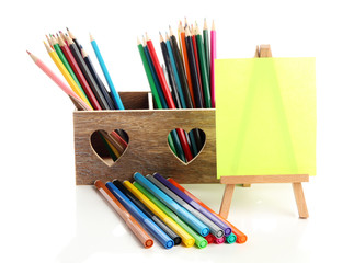 Fototapeta premium Different pencils in wooden crate and easel, isolated on white