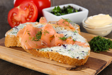 Fish sandwiches on cutting board on wooden table