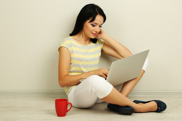 Beautiful young woman sitting with notebook in room