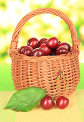 Cherry berries in wicker basket on table on bright background