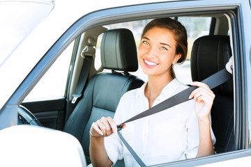Attractive young woman in a car fastens seat belt