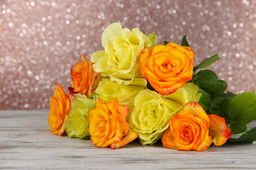 Beautiful bouquet of roses on table on brown background