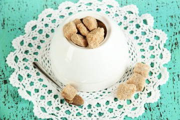 Unrefined sugar in white sugar bowl on wooden background