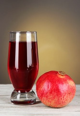 Glass of fresh garnet juice on table on gray background