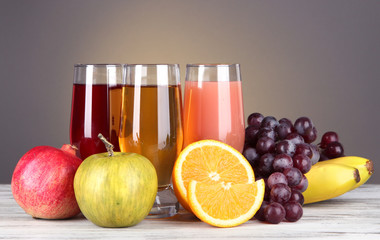 Glasses of fresh juice on table on gray background