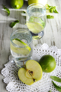 Glasses of cocktail with lime on napkin on light wooden table