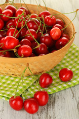 Cherry berries in wicker basket on wooden table close up