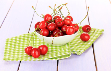 Cherry berries in bowl on wooden table close up