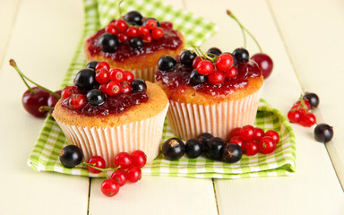 Tasty muffins with berries on white wooden table