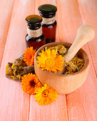 Medicine bottles and calendula flowers on wooden background