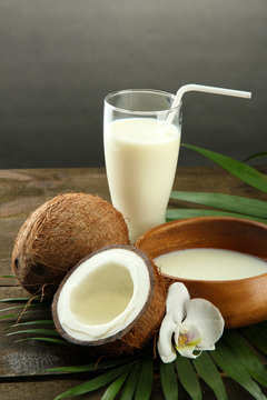 Coconut with glass of milk,  on wooden table, on grey