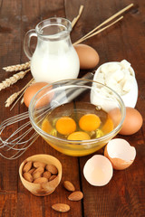 Broken egg in bowl and various ingredients next to them