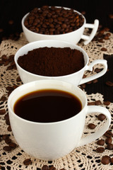 Different types of coffee in three cups on wooden table