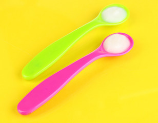 Color spoons for baby food on yellow background