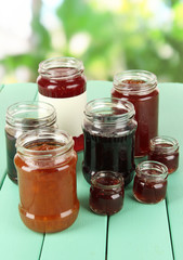 Tasty jam in banks on table on bright background