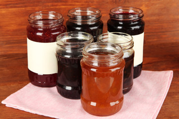 Tasty jam in banks on wooden background