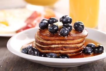 Close up of plate with pancakes, juice and eggs with bacon.