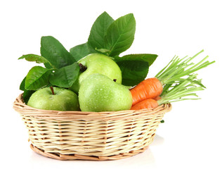 Juicy green apples and carrots with leaves in basket, isolated
