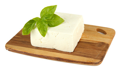 Sheep milk cheese with basil on cutting board, isolated on
